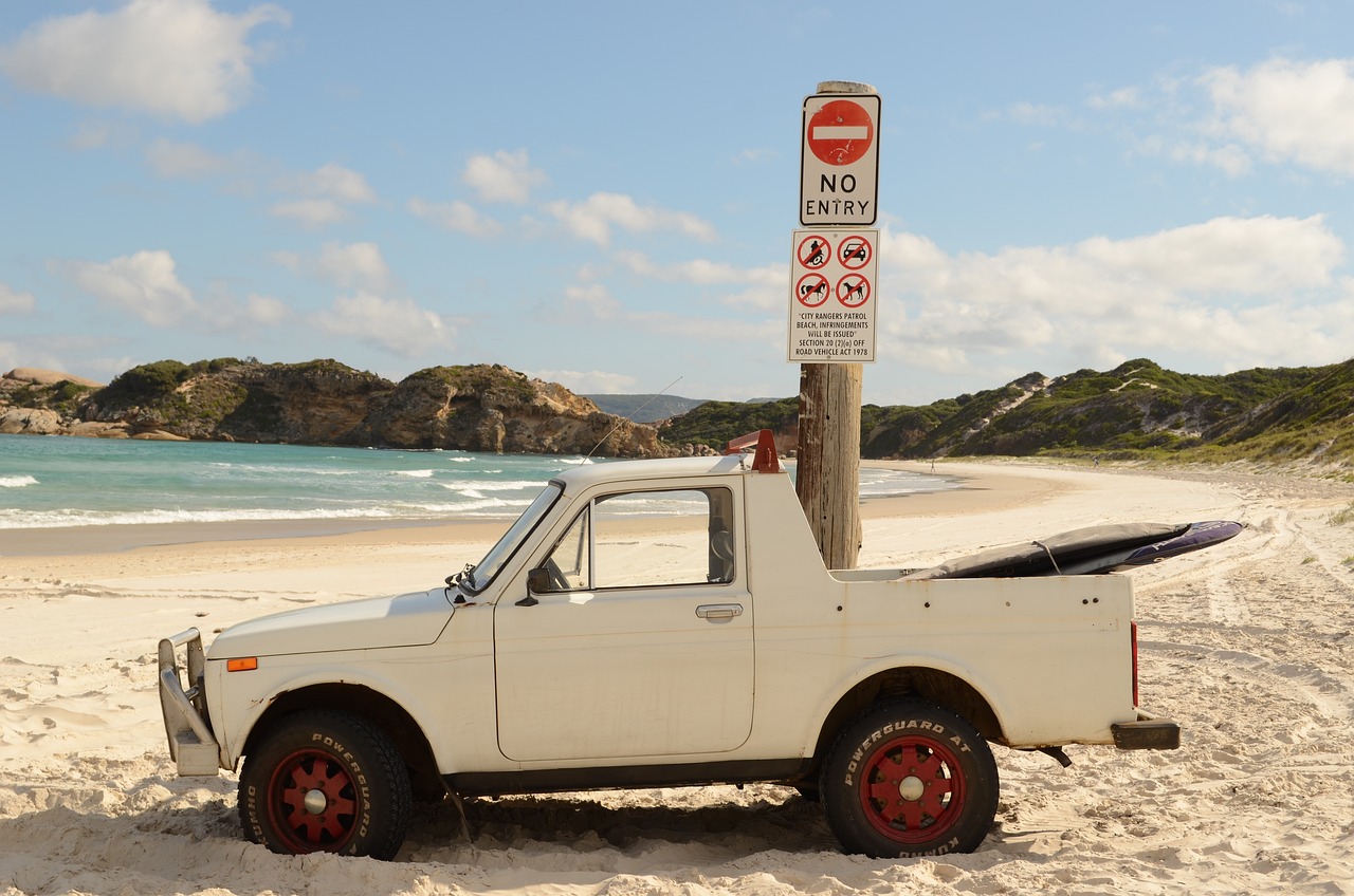 auto op het strand met verbodsborden erachter